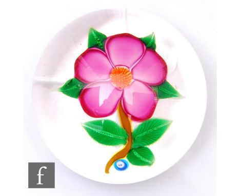 A contemporary John Deacons glass paperweight of domed form, internally decorated with a large stylised pink lamp work flower