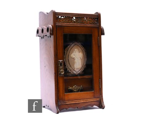 An Edwardian oak smoker's cabinet fitted with a single drawer bellow a gallery and two hinged folding pipe racks with a Doult