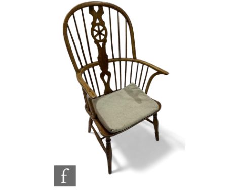 A 19th Century ash and elm comb and wheel back Windsor elbow chair on splayed legs united by a turned H stretcher. Condition 