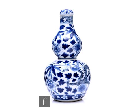 A Chinese Kangxi style double-gourd form vase, the blue and white vase surmounted by a domed cover, decorated with a four-cla