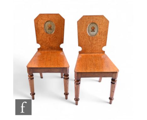 A pair of Victorian light oak hall chairs, the angled backs recessed with an oval panel painted with a wheat sheaf on a pale 