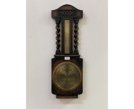 An early 20th century oak cased aneroid barometer and thermometer, the floral carved case with spiral turned pilasters having