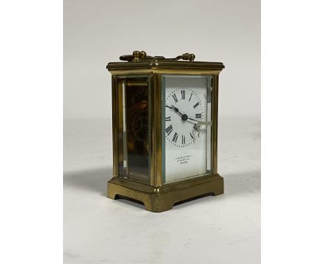 A brass carriage timepiece, mid 20th century, the case with swing handle over oval view window to top, and inset bevelled gla