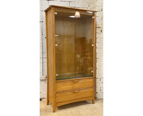 Ercol, a late 20th century blonde elm display cabinet, two glazed doors enclosing three adjustable glass shelves, with two dr