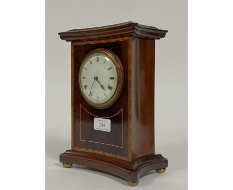 An Edwardian mantel time piece clock of concave rectangular form, the case inlaid with satinwood cross bands, standing on bra