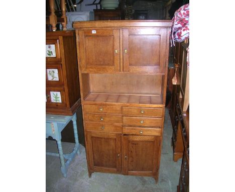 A small vintage oak freestanding side cabinet partially enclosed by two pairs of panelled doors and six central drawers benea