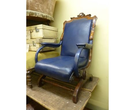 An unusual Victorian walnut rocking chair with X-shaped frame, carved detail and upholstered seat, back and arm panel