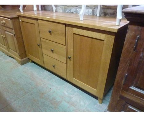 A good quality contemporary light oak sideboard fitted with three central inverted graduated drawers flanked by cupboards enc