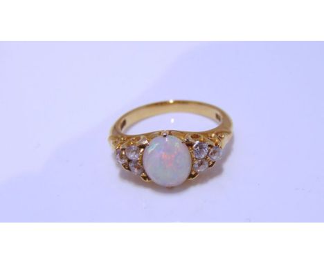 An Edwardian style opal and diamond ring, centred with an oval cabochon opal weighing approximately 1.38cts, flanked to each 