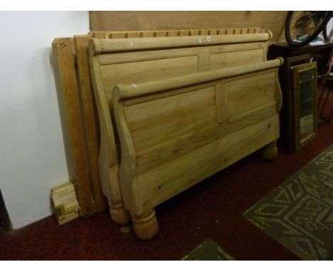 A stripped continental 5ft sleigh bed with shaped outline and heavy turned supports, complete with side adjoining rails and l