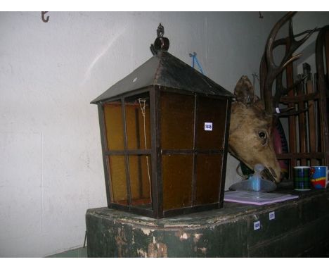 A hanging porch lantern, steel framed, square tapered with glazed panels beneath a triangular shaped roof with ring finial fi