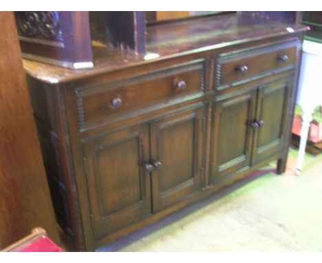 A dark stained elm sideboard, probably Ercol, enclosed by two pairs of rectangular moulded panelled doors beneath two frieze 