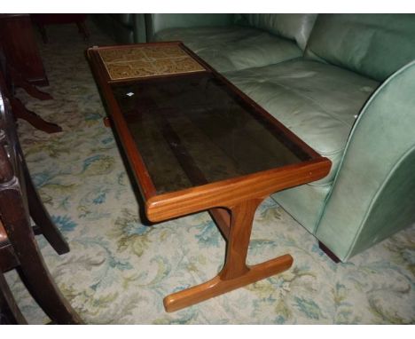 A G plan teak coffee table of rectangular form, the top inset by tylised floral tiles and inset smoke glass panel raised on s