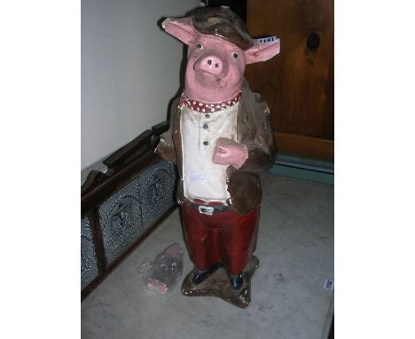 A vintage plaster butchers shop window model in the form of a porker dressed in trousers and jacket and wearing a flat cap