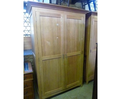 A good quality contemporary light oak bedroom pair comprising wardrobe with swept overhanging cornice, over a pair of full le