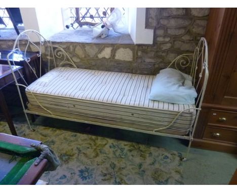 A vintage cast iron folding single bedstead, the arched headboard with simple scrollwork detail, complete with mattress