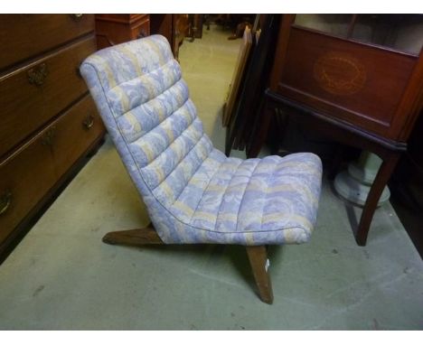 A low vintage chair with angular upholstered seat and combined back raised on tapered supports 