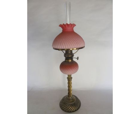 A brass oil lamp marked Zimmermann & Co, London to burner, supporting an opaque and cranberry tinted shade and matching bulbo