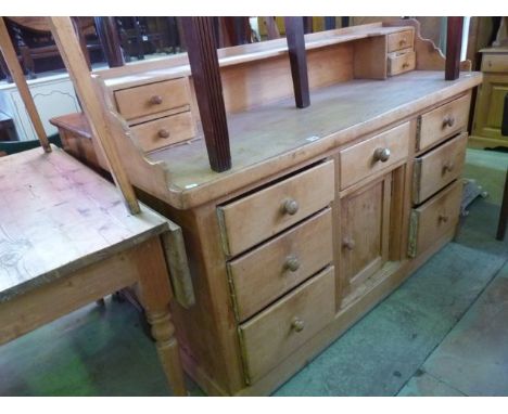 A Victorian stripped pine kitchen dresser, the base enclosed by an arrangement of seven drawers flanking a central slightly r