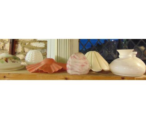 A quantity of glass light shades to include opaque examples of varying form, an example with flared rim on a red ground with 