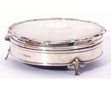 George V silver ring box of circular form with engine turned decoration to hinged lid, applied with a scroll border, standing