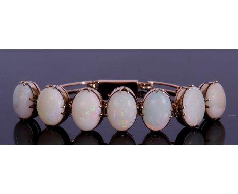 Articulated opal bracelet featuring seven graduated oval cabochon opals, each in cut down settings, joined each side by three