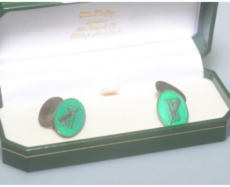 Cricket interest: a pair of silver and green enamel cufflinks, decorated with stumps, bat and ball, marked silver
