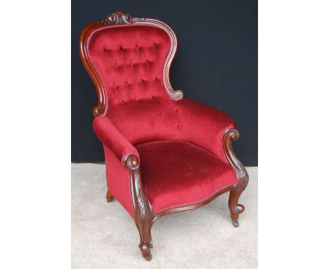 Victorian button-back armchair, the carved top rail over cushioned arms and floral carved frieze raised on cabriole legs with