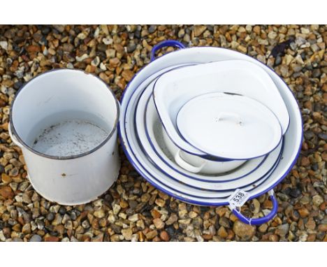 Eight white enamel pots with blue rims, featuring a twin-handled example, largest approx 47cm wide 