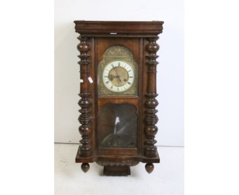 An antique wooden cased wall clock with brass and enamel dial, Roman numeral markers, complete with pendulum. 