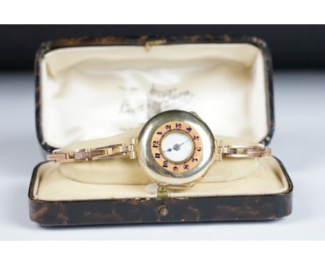 An Edwardian enamelled 9ct gold half hunter wristwatch, white enamel dial with black arabic numerals and poker hands, outer c