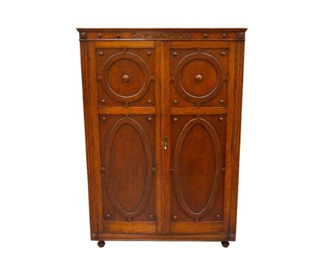 1920's CARVED OAK WARDROBEwith a moulded and carved top above a pair of panelled carved doors opening to reveal a mirrored in