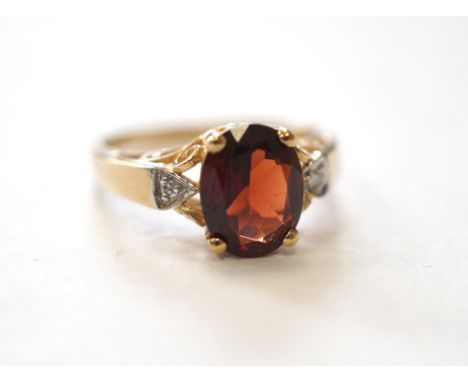 GARNET AND DIAMOND DRESS RINGthe central oval cut garnet flanked by a diamond to each side, on ten carat gold shank, ring siz