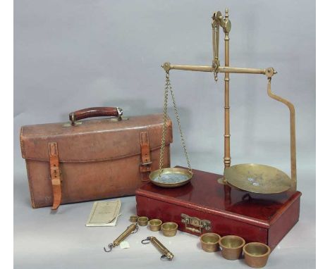 A SET OF LATE VICTORIAN BRASS TRAVELLING SCALES with seven brass weights and two spring balances, mahogany box base and leath