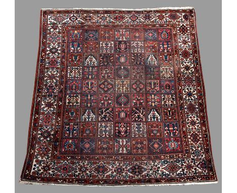 A BAKHTIARI CARPET in tones of red, cream, blue and brown with floral border (general wear, especially in centre) 11' 1" (332