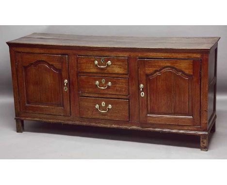 A GEORGE III OAK DRESSER BASE with three drawers flanked by cupboards with fielded panel doors width 67" (170cm)