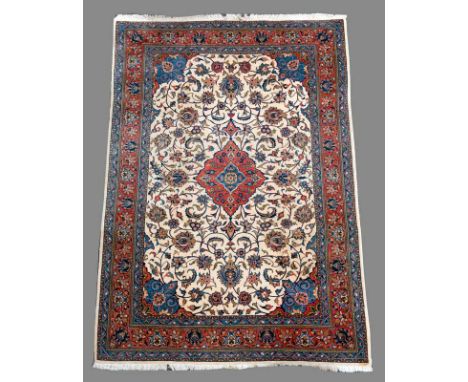 A PERSIAN SMALL CARPET with cream field, rust red and blue border and floral scrolls 10' 3" (314 cms) x 6' 9" (206 cms)