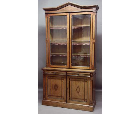 A VICTORIAN INLAID OAK BOOKCASE the glazed top enclosing shelves with leather fringes and with architectural pediment, the ba