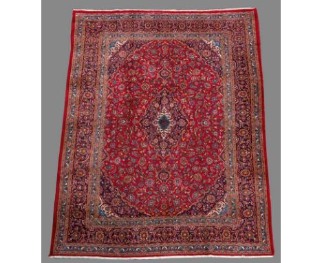 A PERSIAN STYLE CARPET red ground, floral field with red, blue and cream spandrels scrolling floral dark blue border 12' 9" (