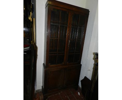 A 1920s Art and Crafts oak bookcase with two glazed doors above shelved cupboard. H: 184cm L: 84cm W: 24cm
