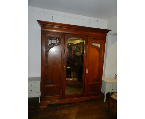 A late Victorian walnut triple wardrobe in the Art Nouveau taste, having a dentil moulded cornice above two panelled doors, r