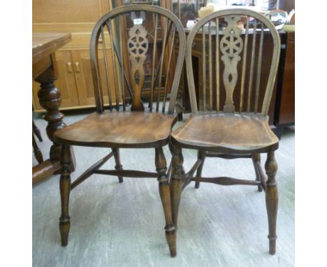 A set of four modern beech and elm framed Windsor, hoop, stick and wheelback chairs, the solid wedge back seats raised on rin
