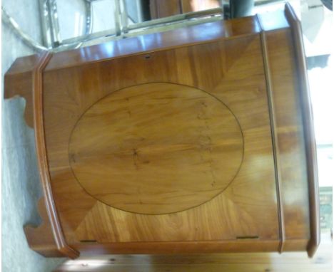 A modern yew wood finished bow front corner cupboard with canted flanks, enclosed by a full height door, raised on bracket fe