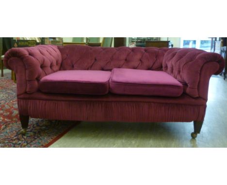 A late Victorian/Edwardian two person Chesterfield, part button upholstered and pleated in deep red dralon with two fitted se