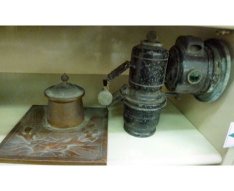 An early 20thC Joseph Lucas black painted, steel cased patent carbide lamp; and a contemporary spot hammered and embossed cop