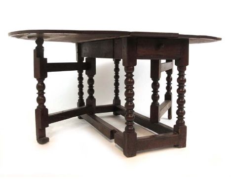 An 18th century and later oak drop leaf table, the oval top over two end drawers on bobbin turned supports and moulded stretc