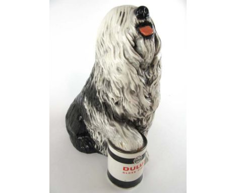 A large ceramic model of 'The Dulux Dog' with paw resting on paint tin. H. 33 cm. CONDITION REPORT: No obvious damage. 