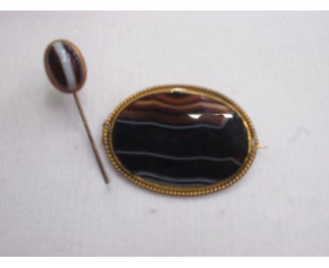 An oval agate brooch having a yellow metal mount with rope decoartion and a similar stick pin