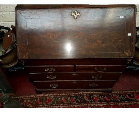 A GEORGIAN SLOPE FRONT OAK BOOKCASE, the interior fitted with various pigeon hole compartments, drawers and central cupboard,