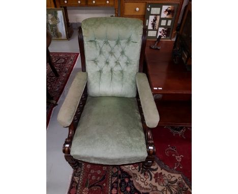 A VICTORIAN ARMCHAIR, with button back, padded seats and elbow rests, covered in green fabric, raised on front turned legs. (